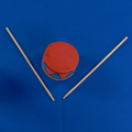 Red toy drum with two sticks on a blue background